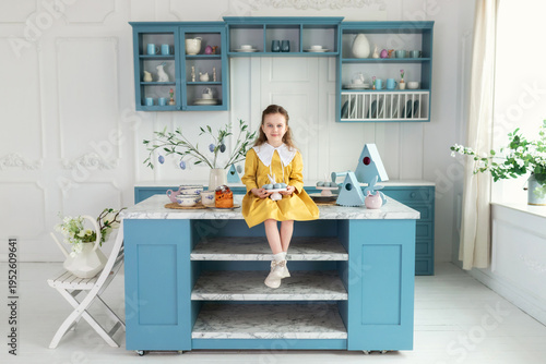 Wallpaper Mural Little Girl playing with easter bunny. Young girl sit on kitchen with easter cake, decorations, spring flowers, easter eggs and bunny. Child Girl in yellow dress holding toy easter rabbit in hands. Torontodigital.ca