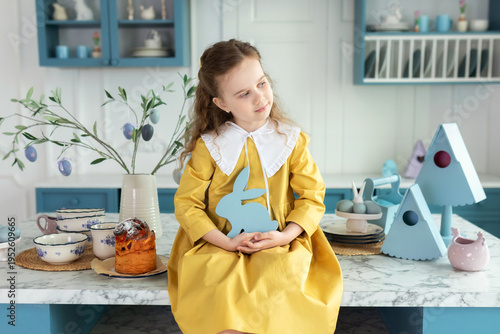 Wallpaper Mural Little Girl playing with easter bunny. Young girl sit on kitchen with easter cake, decorations, spring flowers, easter eggs and bunny. Child Girl in yellow dress holding toy easter rabbit in hands. Torontodigital.ca