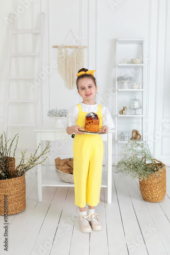 Wallpaper Mural Cute girl in yellow overalls with easter cake in hands. Smile child holding easter pie, celebrating easter and spring. Happy little girl holding a baking with baked cake in her hands on rustic kitchen Torontodigital.ca