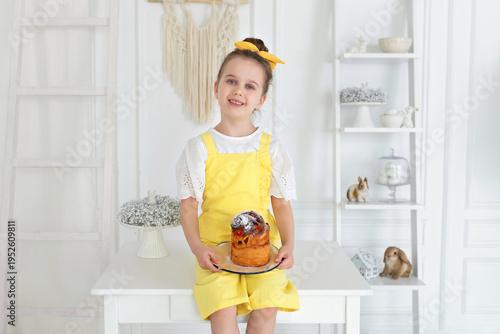 Wallpaper Mural Cute girl in yellow overalls with easter cake in hands. Smile child holding easter pie, celebrating easter and spring. Happy little girl holding a baking with baked cake in her hands on rustic kitchen Torontodigital.ca