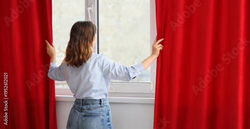 Young woman opening red cur...
