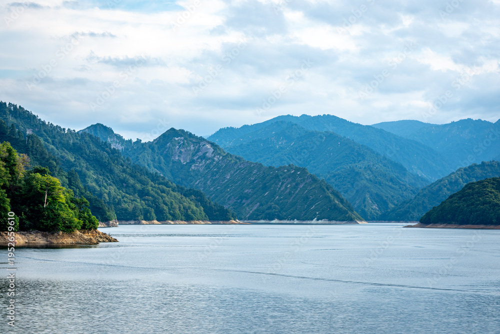 Obraz premium 新潟県奥只見湖の雄大な山並みと水面、夏の終わりの曇り空