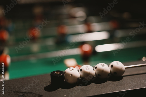 Canvastavla Foosball table with white and black balls in focus, indoor game room setting