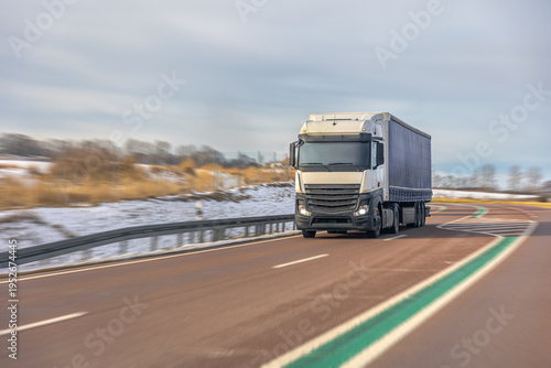 Freight truck driving on winter highway through snowy landscape. Logistics delivery transport.