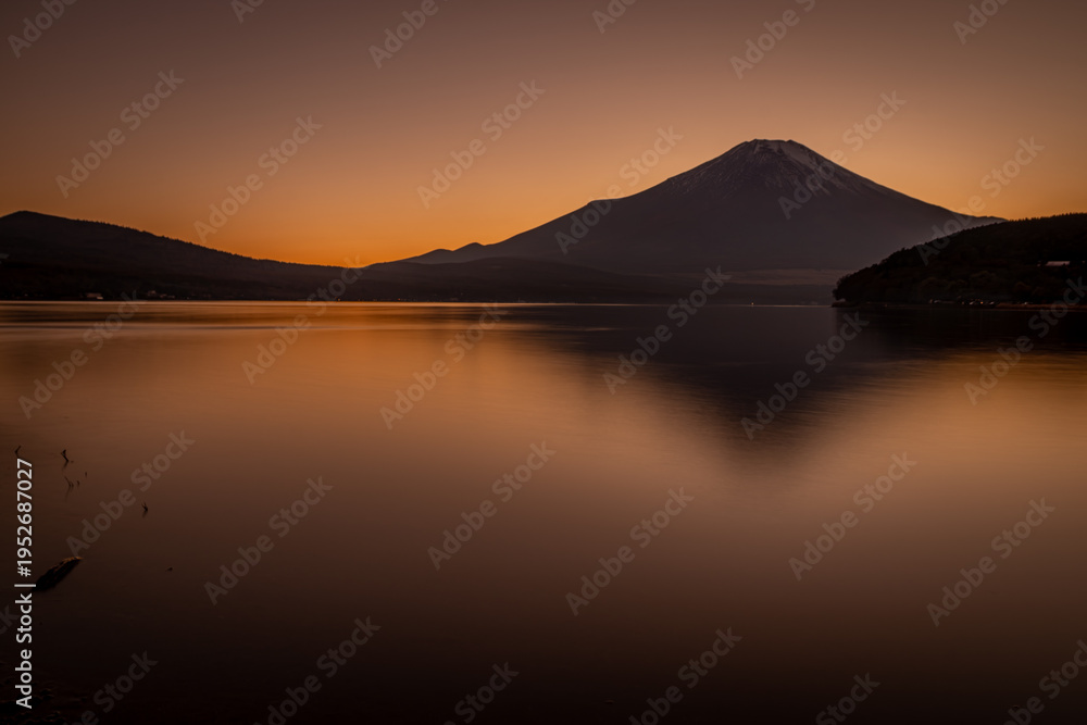 Obraz premium 夕暮れの山中湖に映る富士山と黄金色に染まる静かな水面