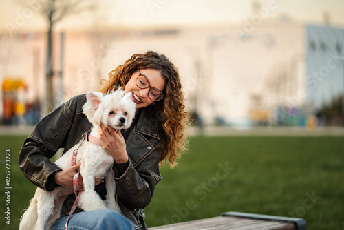Картината върху платно Young woman enjoying time with cute white dog in park