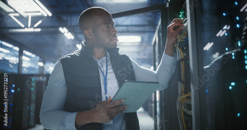 Data center technician inspects server racks, checks network cables, and uses a tablet to monitor hardware status. Rows of illuminated servers, digital infrastructure, and secure network operations.