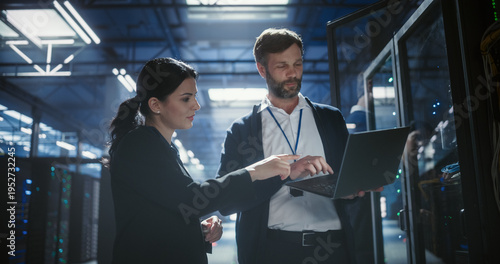 Quadro su tela Two specialists use a laptop to review server rack electronics, check device con