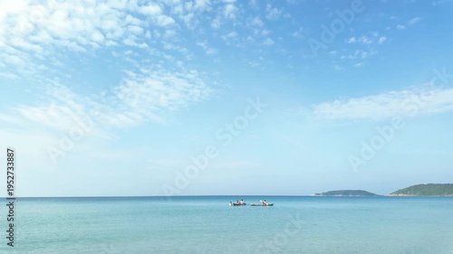 Tourists paddling a canoe on the clear blue sea under a bright sunny sky.