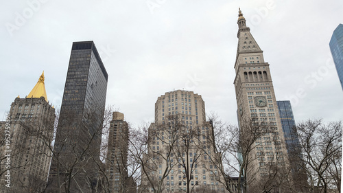 Historic church steeple rising among modern skyscrapers in New York City showcasing dramatic architectural contrast under overcast urban winter skyline, travel USA