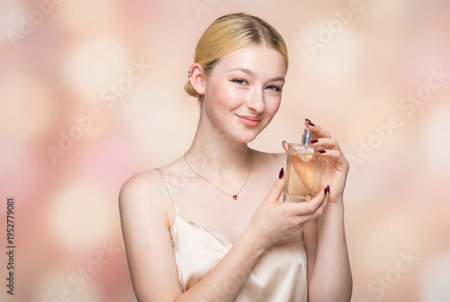 A beautiful sexy lady in an elegant nude bodysuit holds a bottle in her hands. Fashion beauty portrait of fashion model