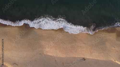 Aerial bird's eye view of golden sand beach meeting the turquoise ocean waves