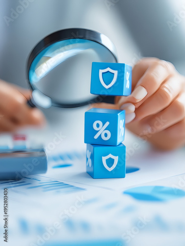 up of a financial analyst hand holding a magnifying glass over stacked cubes with icons representing shield, percentage, and currency, symbolizing credit risk and insurance planning. Neutral 