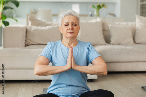 Yoga mindfulness meditation. Senior adult mature woman practicing yoga at home. Mid age old lady sitting in lotus pose on yoga mat meditating relaxing. Older middle aged woman doing breathing practice