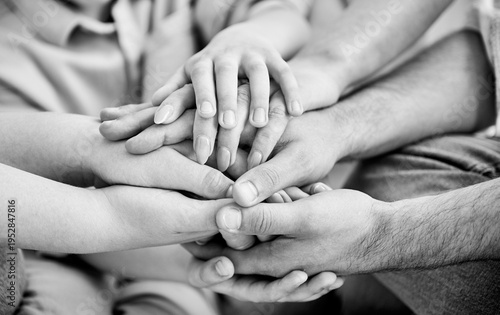 Close-up of several hands placed on top of one another in stack. All family members showing their support to each other. Concept of togetherness, unity, teamwork, family. Black and white image.