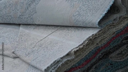 Industrial carpet manufacturing process showing stacks of finished rugs in a factory warehouse setting.