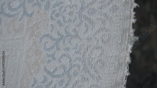 Detailed close up of traditional floral carpet patterns hanging in a large textile manufacturing facility.