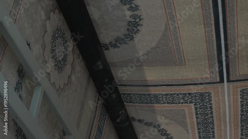 Large patterned carpets hanging from industrial metal racks during the manufacturing process in a factory.