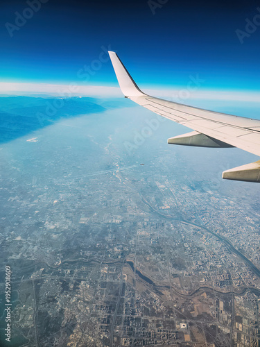 Aeroplane window view and left wing flying over above the sky cloud with city landscape below
