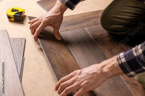 worker installing new vinyl tile wood texture flooring in a herringbone pattern. home improvement