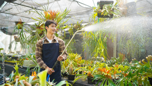 Foto A gardener with a watering hose and a sprayer water working in greenhouse and watering fern