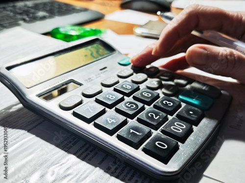 Valokuva Person using a calculator to perform a calculation in a workspace setting in day