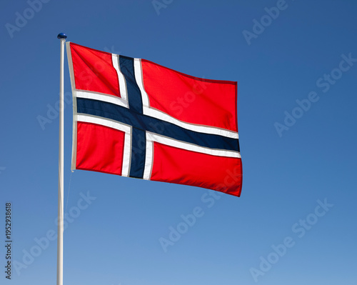 Norwegian national flag waving in the wind against blue sky