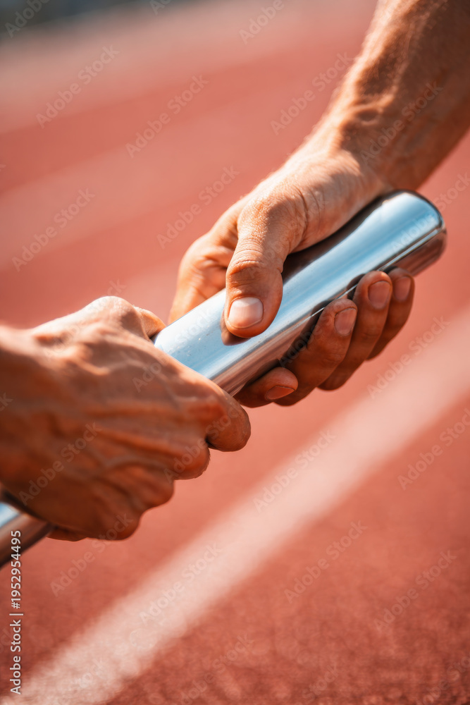 Fototapeta premium Hands exchanging a relay baton on a running track