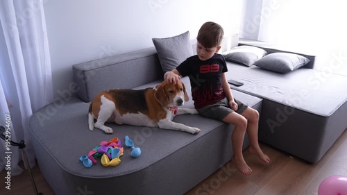 A child and a beagle are sitting on a bed