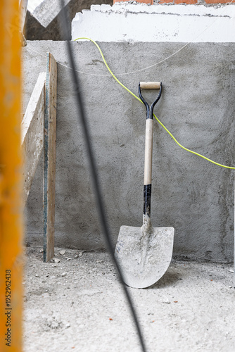 Shovel standing at construction site with building foundation