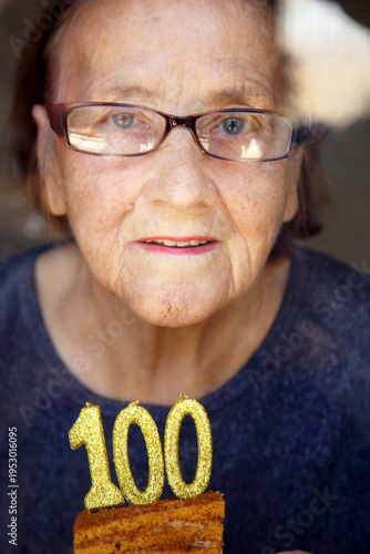 Foto Portrait of an elderly woman with glasses holding anniversary candles
