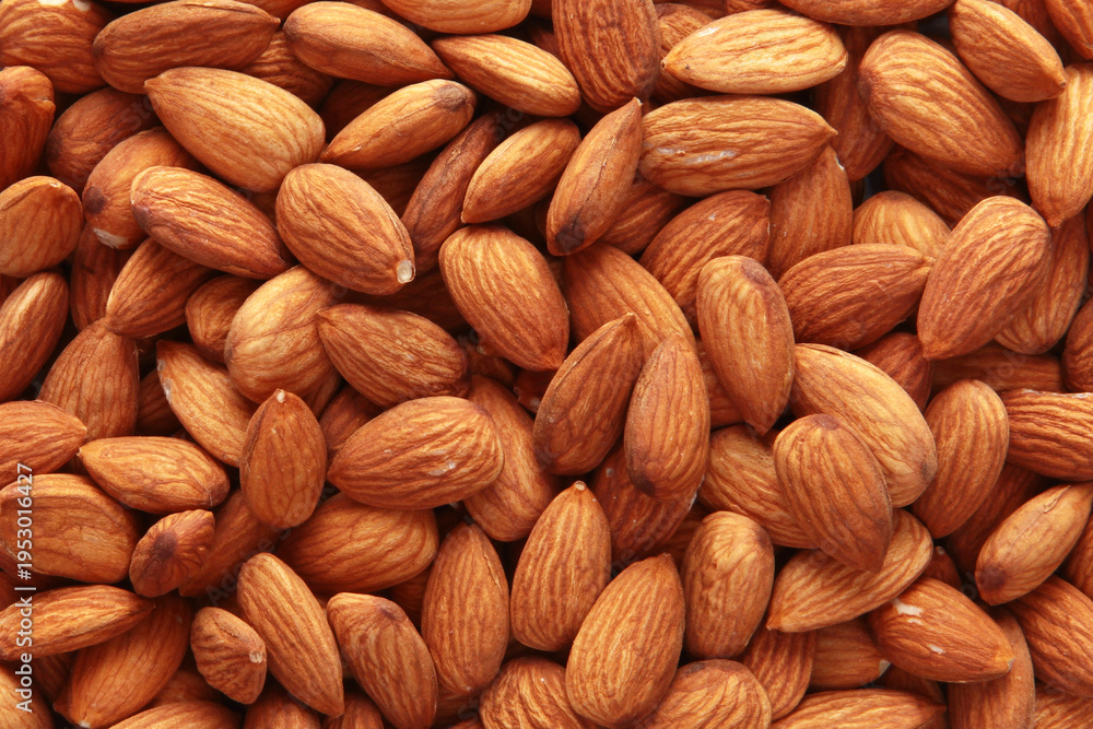 Fototapeta premium Peeled almond kernels. Close-up. The texture of the nut. A large number of peeled almonds. A vegan dish. View from above. Healthy eating. An energy product. Top view.