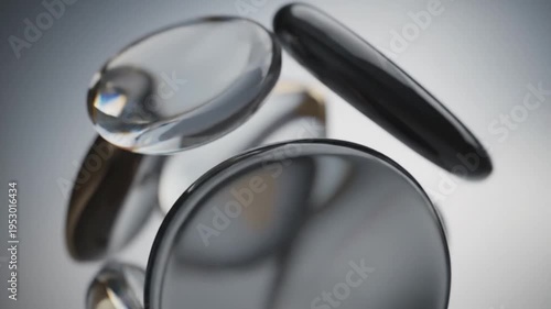 Abstract composition featuring smooth black and clear oval shapes floating gracefully in a luminous minimalist environment