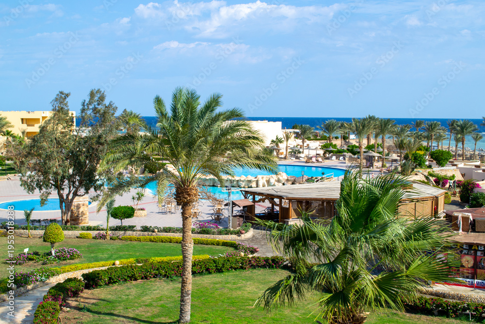 Fototapeta premium EGYPT, Marsa Alam, January, 2022: Swimming pool, territory with palms and sea view in Egyptian hotel