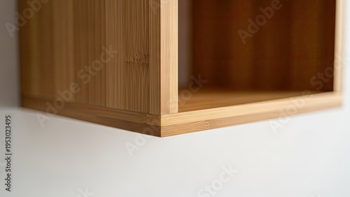 Close-up of a minimalist, light-wood square shelf, mounted on a white wall