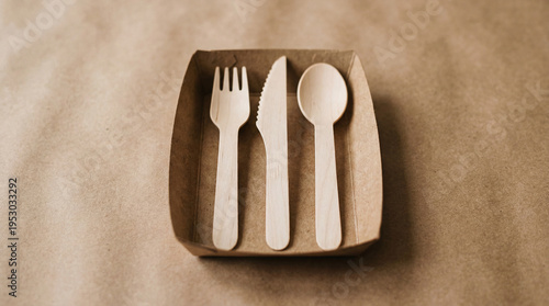 Set of wooden utensils placed neatly in a small tray on a brown surface at a casual dining setting