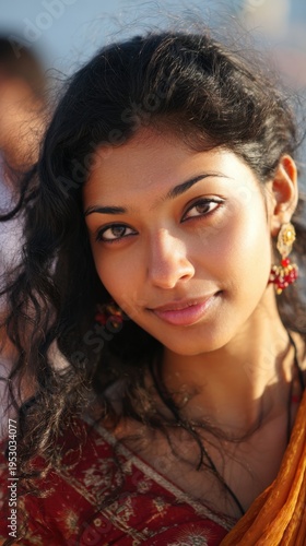 Young woman smiles at the camera during a cultural event in a vibrant setting with natural light and people in the background