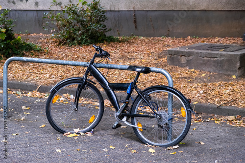 Black Electric Bicycle Locked to Bike Rack in Autumn Setting with parking and urban