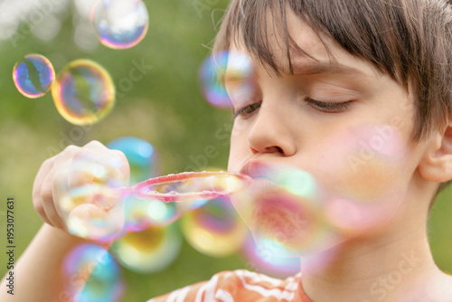 A boy is blowing lots of soap bubbles. Blurred bubbles in the foreground. Boy in focus