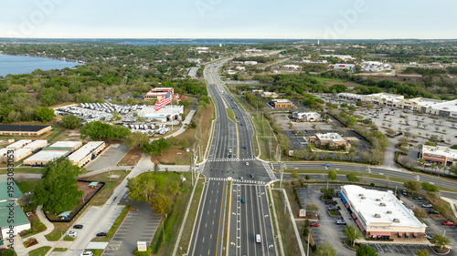 A high-angle drone view features a bustling intersection along Highway 27 in Central Florida, framed by businesses and open landscape.
