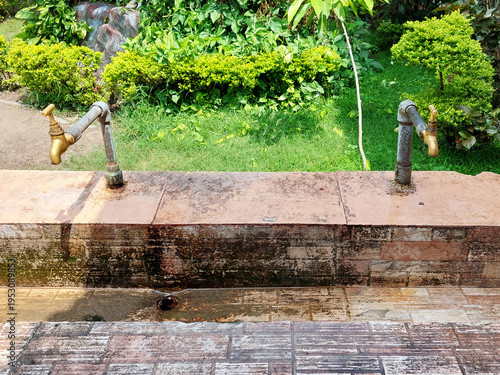 Rustic metal taps on a stone fountain. Outdoor water features. Architecture and construction.