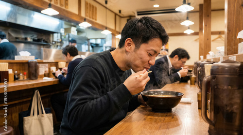 Wallpaper Mural Young japanese man eating hot ramen noodles in a traditional restaurant at the counter, enjoying authentic food Torontodigital.ca