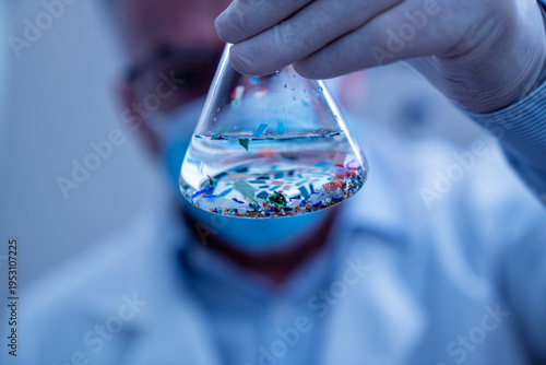 Tableau sur toile Scientist examining microplastic particles in a laboratory flask, studying envir