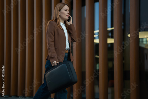 Foto Businesswoman walking and talking on mobile phone