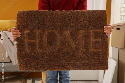 Young woman with doormat in...