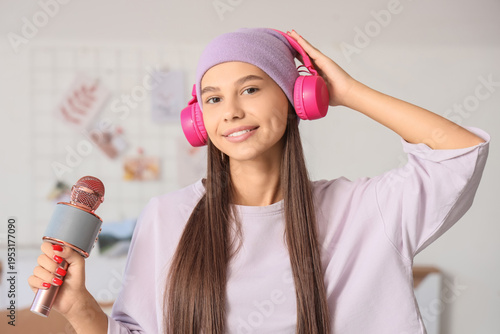 Teenage girl with headphones and microphone listening to music in bedroom
