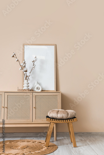 Chest of drawers, stool and vase with cotton flowers in interior of living room