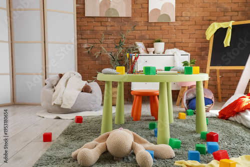 Bilde på lerret Interior of messy children's room with table, scattered clothes and toys