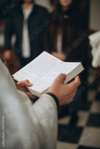 Priest holding open bible during christian church service