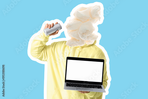 Young man with blank laptop drinking soda on blue background